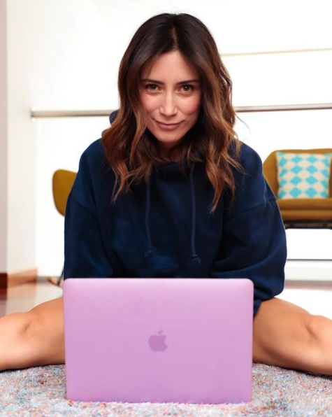 Ana María está sentada en una alfombra. Tiene sus piernas abiertas y en medio, su computador portátil color rosa