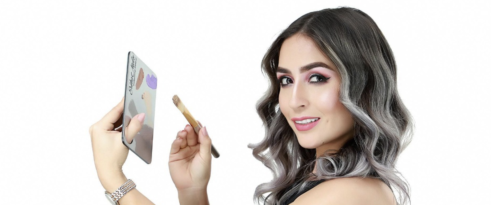 Érika Melo, make-up artist, sostiene una paleta de maquillaje en su mano izquierda y una brocha en su mano derecha, mientras sonríe a la cámara